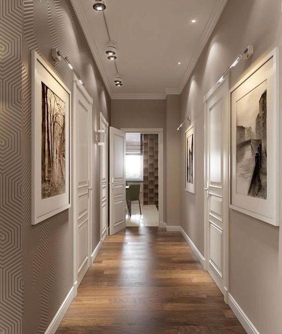 a refined greige corridor with beautiful artworks on the walls and lights and spotlights is a chic and elegant space