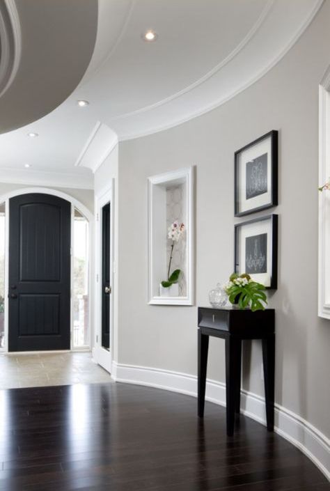 a refined modern entryway with dove grey walls, white molding including crown molding, black and dark touches for a bold contrast is a chic space