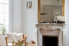 a sophisticated Parisian living room with ornated crown molding, with a refined fireplace and a gorgeous mirror ina  gilded frame, with neutral furniture