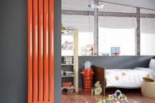 an attic kid’s room with grey walls, simple modern furniture, a vertical orange radiator is a lvoely space with a touch of color