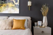 03 a bold bedroom with a graphite grey wall, creamy furniture, creamy and yellow bedding, a bold artwork over the bed