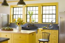 06 a bright farmhouse kitchen with bold yellow cabinets and window frames, grey stone countertops and a large sink