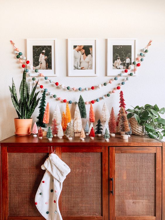 a chic credenza with colorful bottle brush Christmas trees, colorful felt garlands and a polka dot stocking