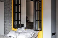 10 a modern industrial bedroom with light grey walls, a grey brick wall, a yellow zone with a window and a yellow bed with grey bedding