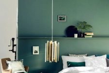 15 a muted green accent wall with a shelf and matching emerald bedding and a pillow