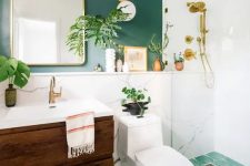 18 a chic modern bathroom with a green accent wall and a green mosaic tile floor, a stained vanity, an arched mirror and potted plants