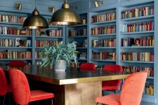 23 a beautiful stone blue home library and home office with lots of built-in shelves, a large refined desk, red chairs and pendant lamps
