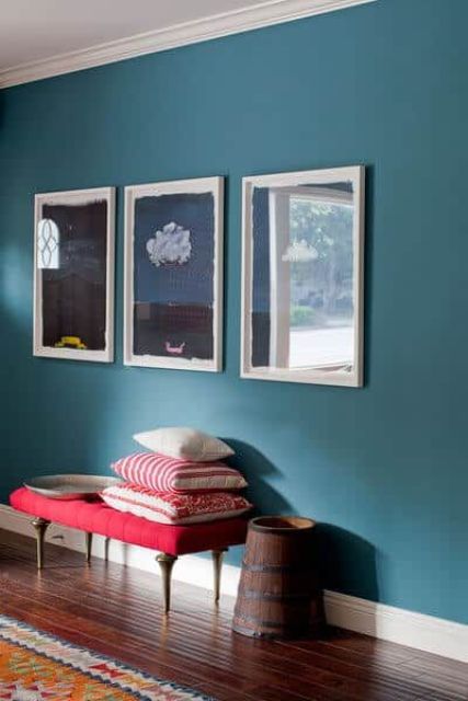 a lovely stone blue space with a navy and white gallery wall, a red bench with bold pillows and a wooden bucket