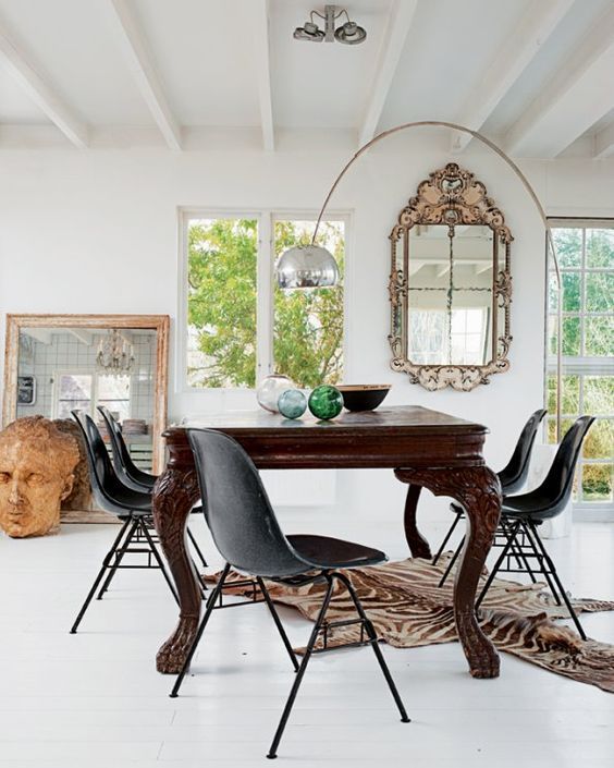 A gorgeous dining room with a vintage dark stained dining table, modern black chairs and a bold accent rug