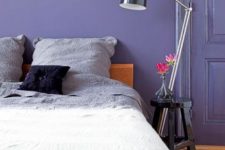 a chic periwinkle bedroom with a matching door, a stained bed with dip-dye bedding and a black nightstand with a black lamp
