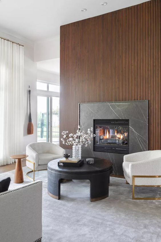 a contemporary living room with a wooden slat wall and a marble fireplace, a black table and neutral chairs is lovely