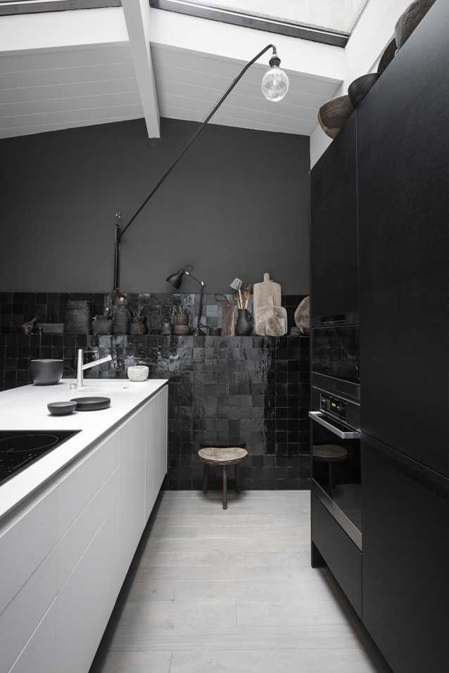 a fantastic kitchen with matte black walls, a gorgeous black zellige tile wall, a white kitchen island and black cabinetry