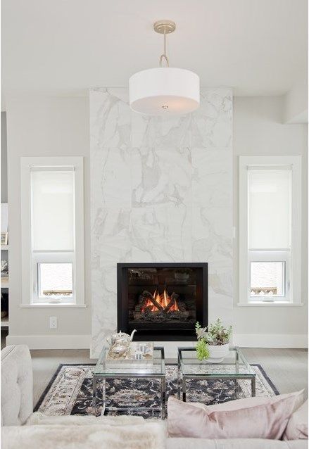 a glam white living room with a white marble fireplace, neutral seating furniture, coffee tables and some decor