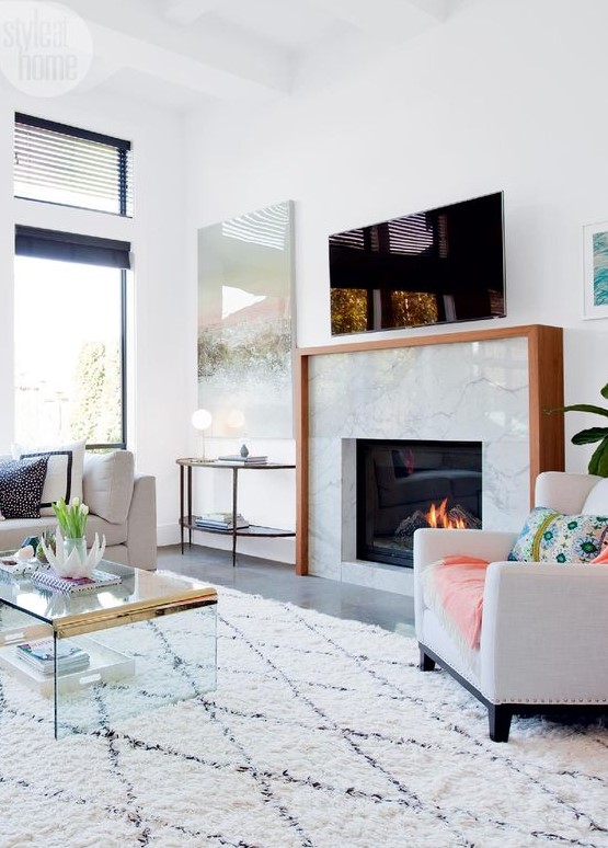 a light filled and welcoming living room with a marble clad built in fireplace with a wooden mantel