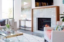 a light-filled and welcoming living room with a marble clad built-in fireplace with a wooden mantel