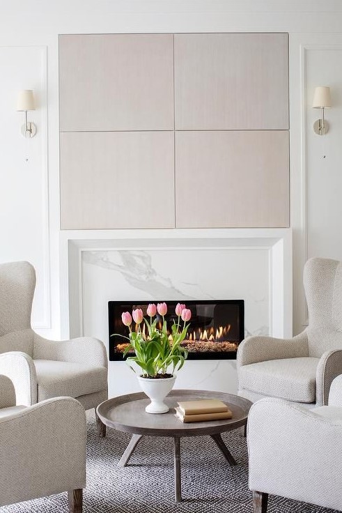 A light filled neutral and pastel living room with a marble clad fireplace and a cool sitting zone by its side