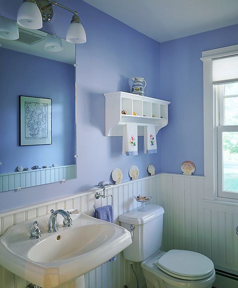 a lovely periwinkle bathroom with white wainscoting, white vintage appliances and a white display shelf plus some seashell decor