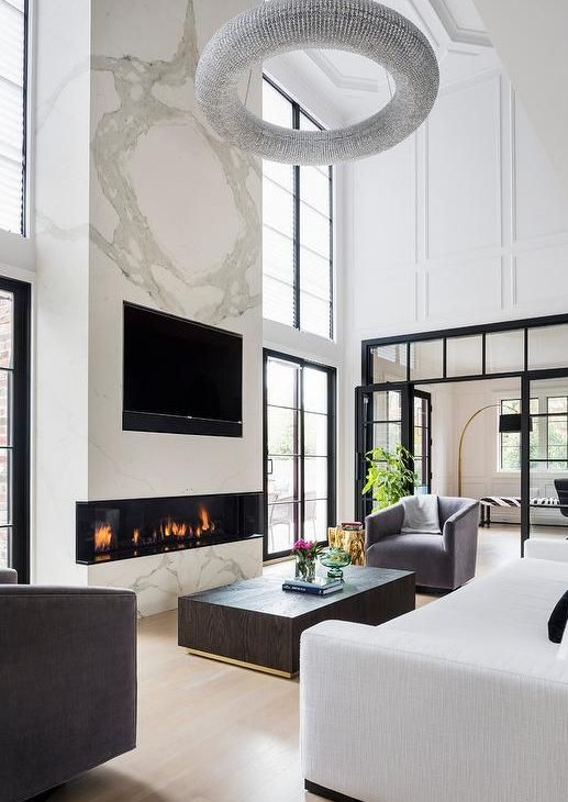a luxurious living room with a large marble slab with a built in fireplace and a TV is the centerpiece of the room