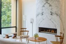 a modern refined living room with a white marble fireplace that warms up the whole space and makes it cozier
