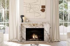 a neutral living room with a marble fireplace, a round coffee table, neutral seating furniture, a large artwork and some decor