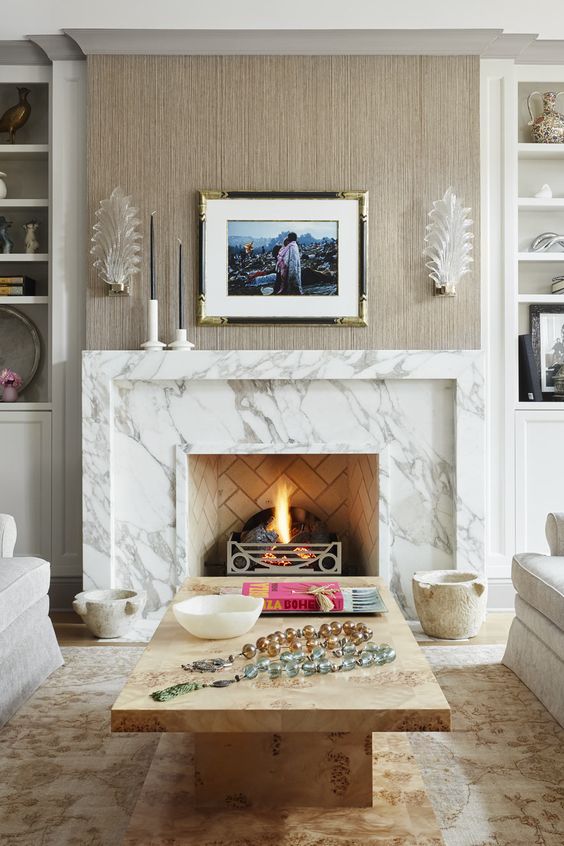a neutral living room with built-in shelves, a white marble fireplace, neutral seating furniture, a stone slab coffee table