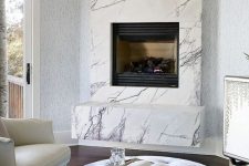 a neutral luxurious living room with a marble clad built-in fireplace and refined leather and velvet furniture