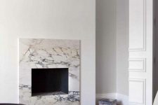 a neutral minimalist living room with a non-working fireplace clad with white marble for a chic and cool touch