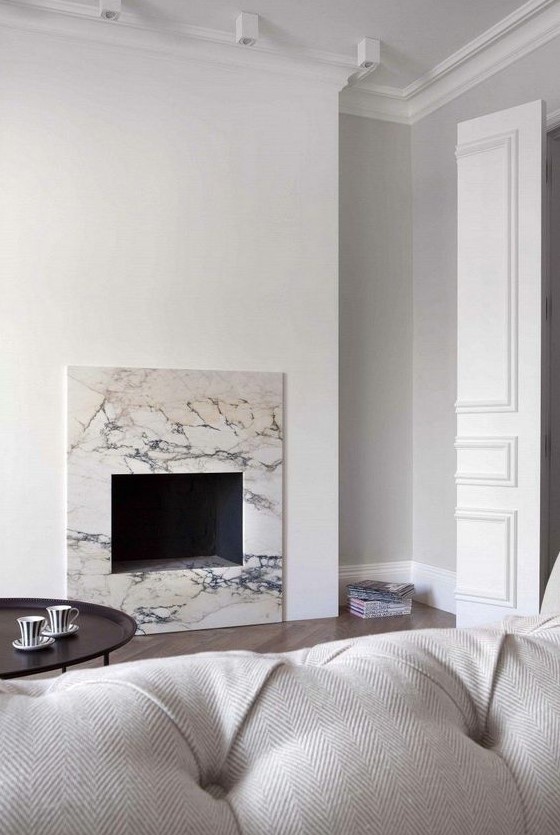 A neutral minimalist living room with a non working fireplace clad with white marble for a chic and cool touch