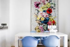 a refined dining space with a simple white table, periwinkle chairs and a bold floral artwork that sets the tone in the room