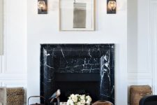 a refined living room with a black marble fireplace, a coffee table with decor, a printed rug and some art