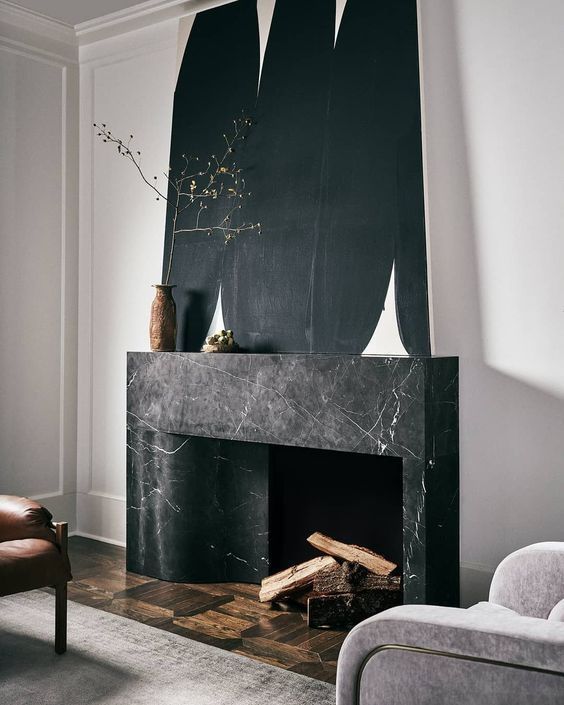 a refined living room with a black marble fireplace, an oversized artwork, neutral furniture and some minimalist decor