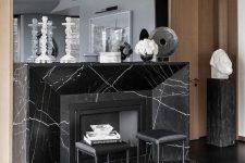 a refined space with a black marble fireplace, black leather sotols and a large mirror is wow