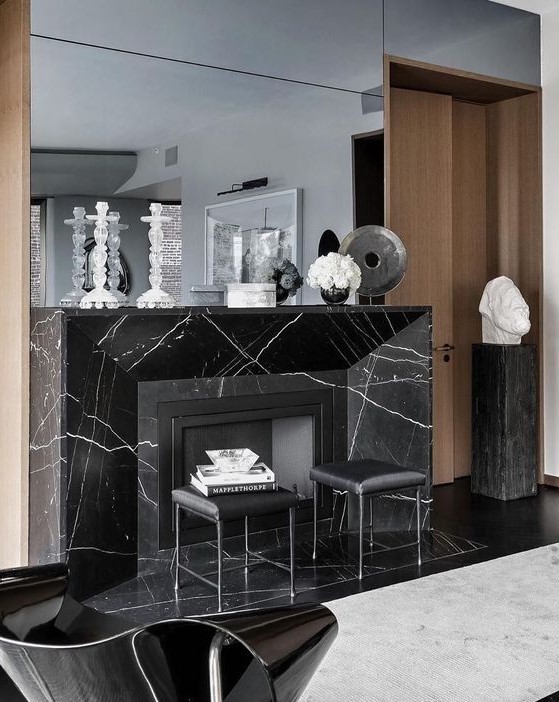 a refined space with a black marble fireplace, black leather sotols and a large mirror is wow