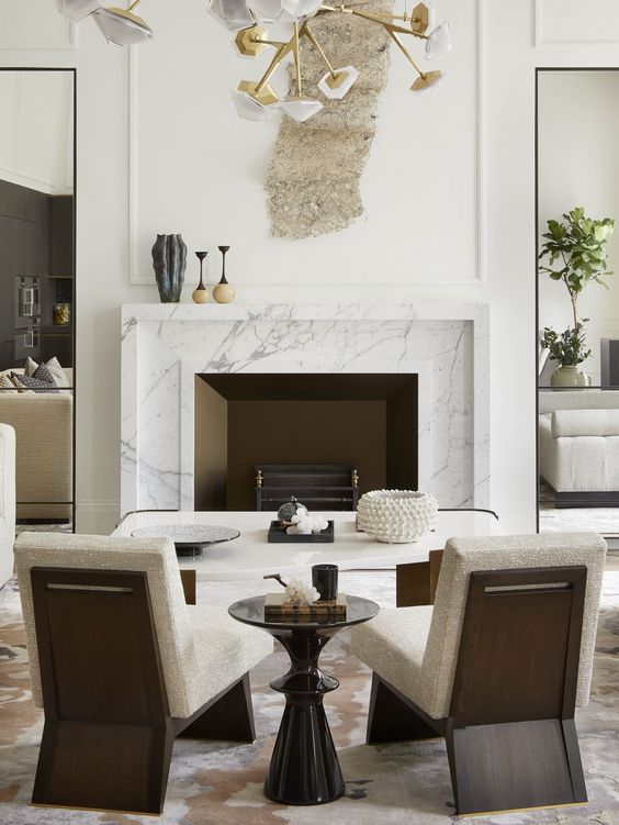 a refined space with a fireplace clad with white marble, a white coffee table, neutral chairs and a black side table