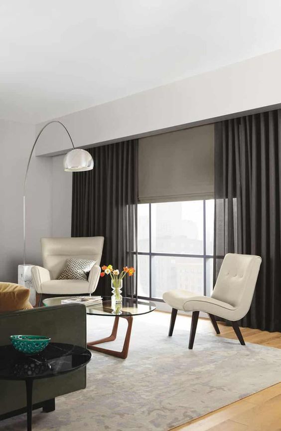 grey fabric blinds and semi sheer graphite grey draperies add drama to this neutral space and make it stand out