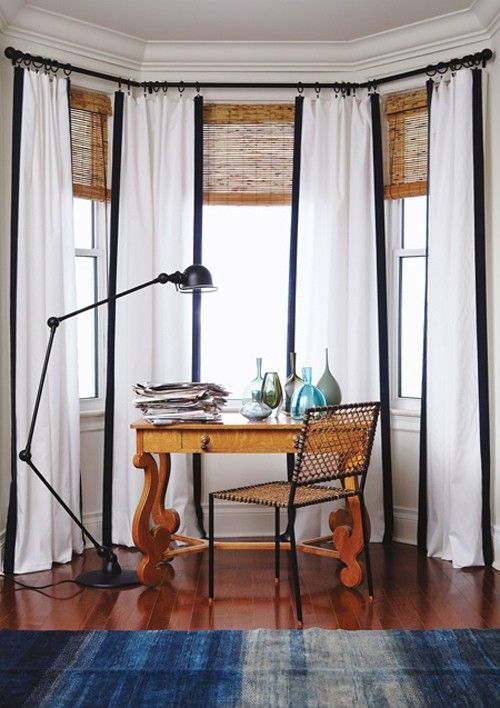 woven shades and white curtains with black rims are a unique combo for this space, and woven shades echo with the stained desk
