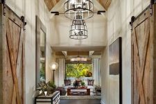 15 a farmhouse space with a dark-stained wooden floor, a light-stained ceiling and sliding doors plus elegant furniture, art and pendant lamps