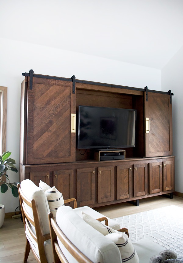 A beautiful and refined vintage dark stained storage unit with sliding doors that hides a TV and makes a statement with its look