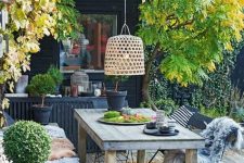 42 a relaxed Scandinavian deck with a built-in bench and a table, a pendant lamp, potted greenery and some trees