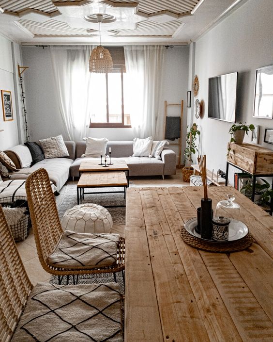 a Scandinavian living room with a rough wood dining table and a matching sideboard, rattan chairs and printed cushions