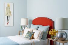 a chic guest bedroom with pastel blue walls, a coquelicot upholstered bed with blue bedding, wooden nightstands and cool table lamps