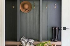a mudroom with slate grey racks and cabinets, a stained bench, a basket for storage and a striped blanket is chic