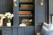 a slate grey bookcase and storage units with brass touches and a matching built-in windowsill daybed are elegant and timeless