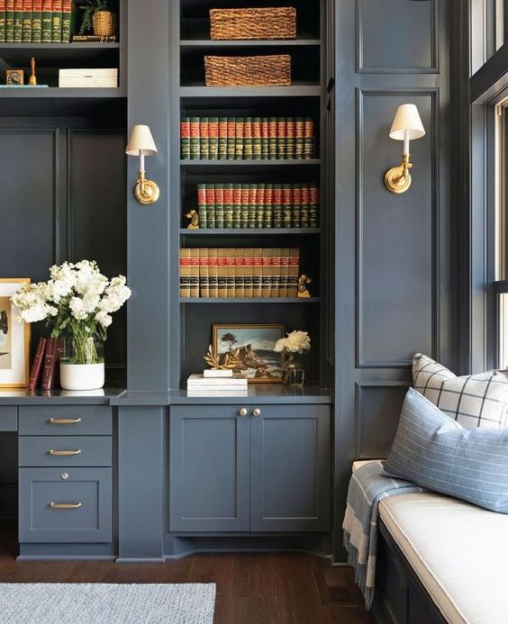A slate grey bookcase and storage units with brass touches and a matching built in windowsill daybed are elegant and timeless