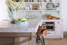 a stylish farmhouse kitchen with aqua tiles and white shelves, white cabinets, a rough wood ceiling, metal pendant lamps and a large kitchen island