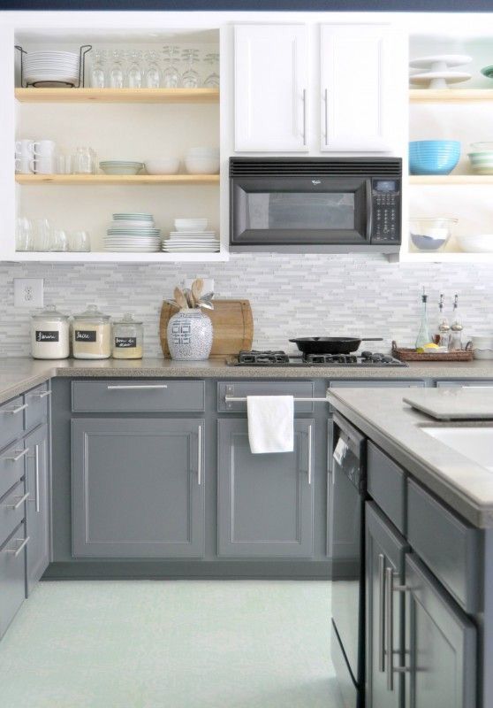 A two tone kitchen with white upper cabinets and grey lower ones, with stone countertops, open shelves and neutral handles
