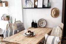 a welcoming Scandinavian dining space with a rough wood table, rattan chairs and a pendant lamp, beautiful plates and striped pillows