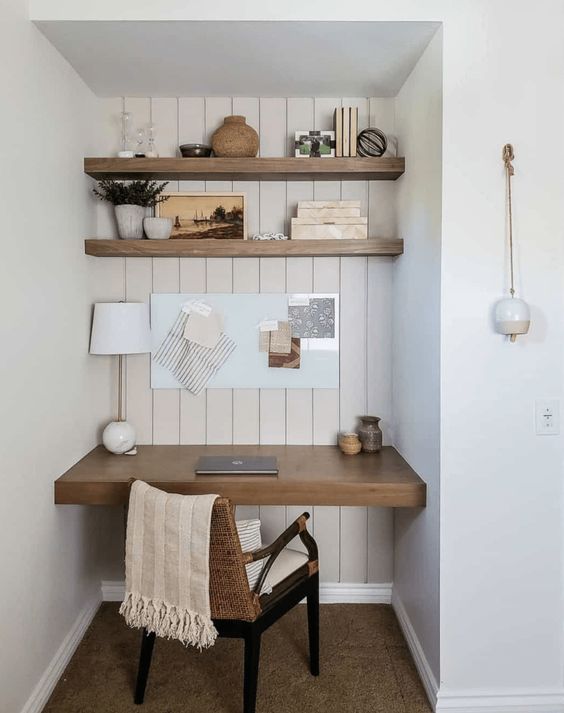 An awkward nook turned into a small working space, with built in shelves and a desk, a woven chair and various decor is cool