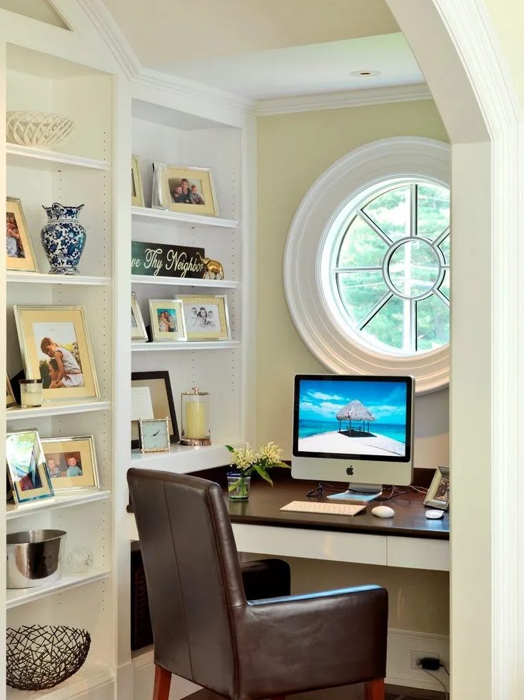 An awkward nook with a porthole window, built in shelves, a built in desk and a leather chair is a cool productive oasis