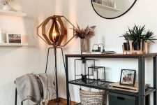 a modern metal and wood console table, potted plants, grass in a vase, some candleholders, a box and a basket plus a very eye-catchy floor lamp